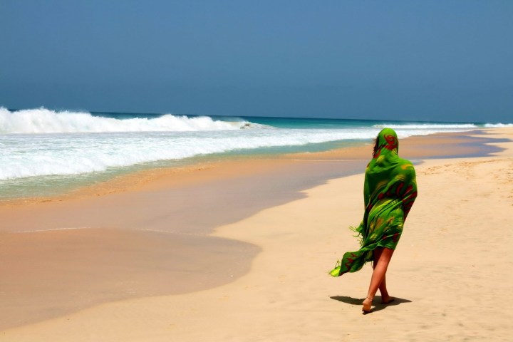 a person walking across a beach next to the ocean
