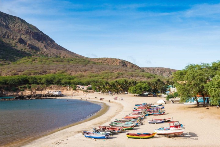 a group of people on a beach with a mountain in the background
