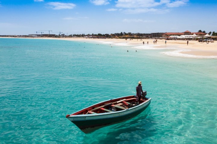 a blue and white boat sitting next to a body of water