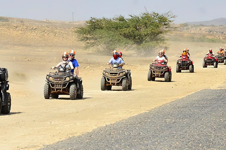 a group of people riding a motorcycle down a dirt road