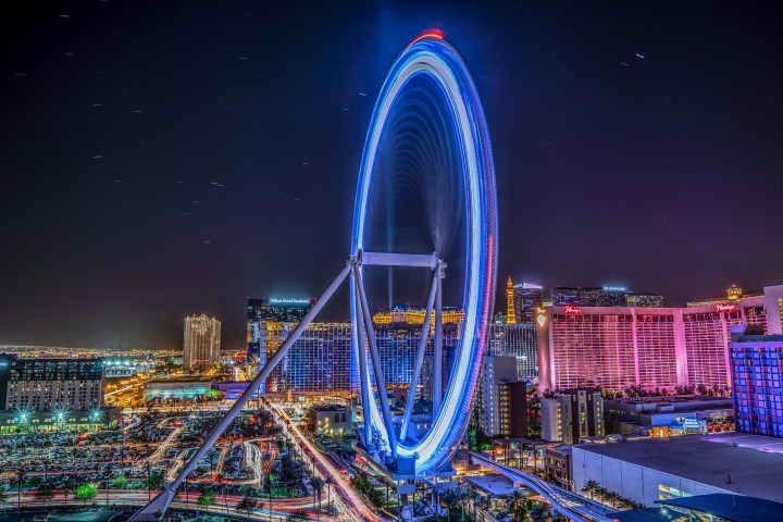 Night view of Ferris wheel and illuminated city skyline with neon lights.