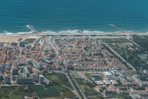 Aerial view of a coastal city with buildings, roads, and shoreline.