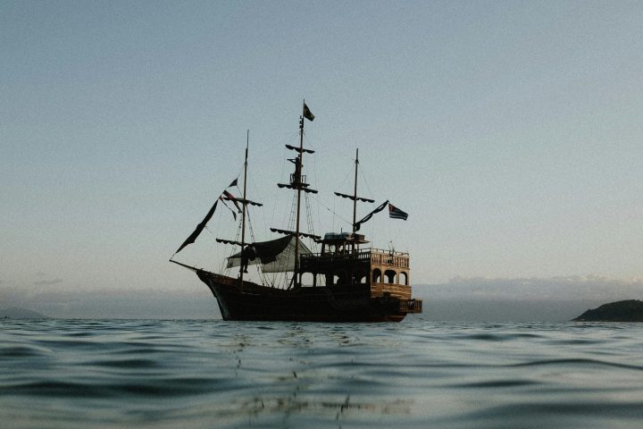 Silhouette of a sailing ship on calm sea at sunset.